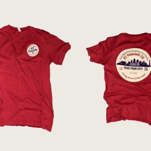 Red KC Pancake Co. Feed Your City t-shirt, front with small logo and back with Kansas City skyline graphic